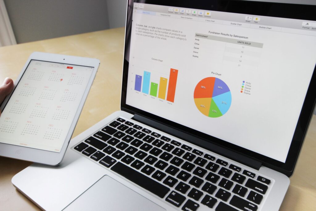 laptop screen showing a chart and data with a person holding a tablet showing a caleendar